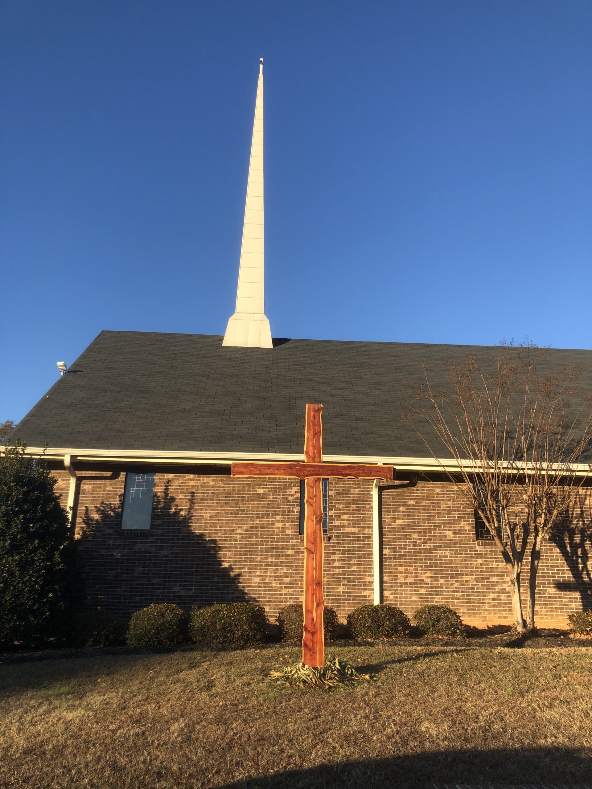 A Presbyterian Church featuring a tall steeple topped with a cross against a clear blue sky.