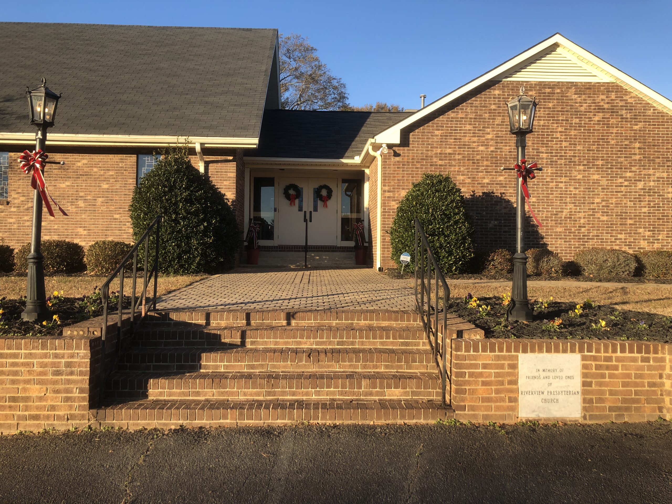 A Presbyterian Church with a tall steeple, perched on a scenic hill, surrounded by greenery and blue sky.